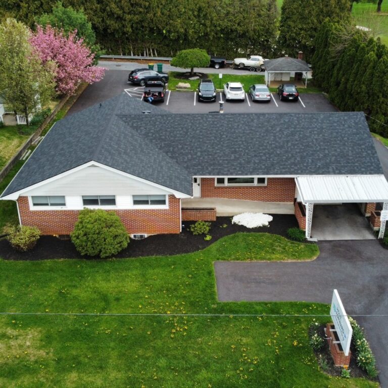 Aerial view of a mid sized commercial building with newly installed shingled rooftop by The Exterior Company
