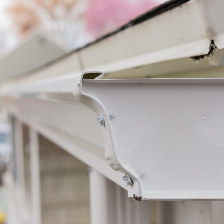 A close up view of a white gutter properly installed on a roof top