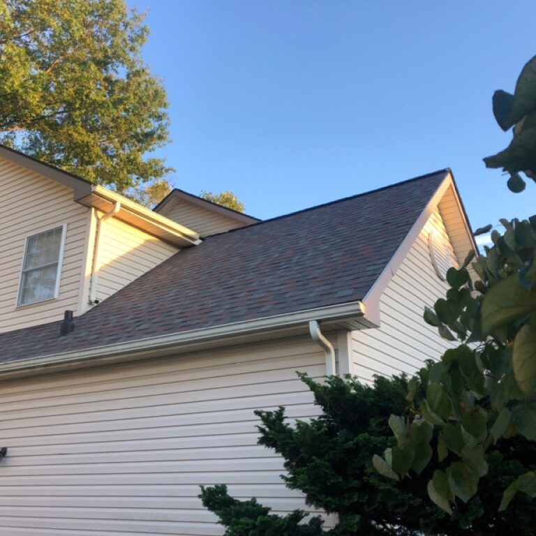 Ground level view of a completed gutter project with a shingled rooftop.