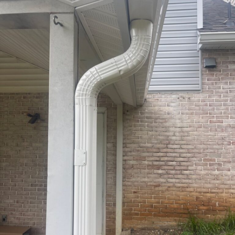 Side view of a newly installed white gutter system on a residential home and front door walkway cover