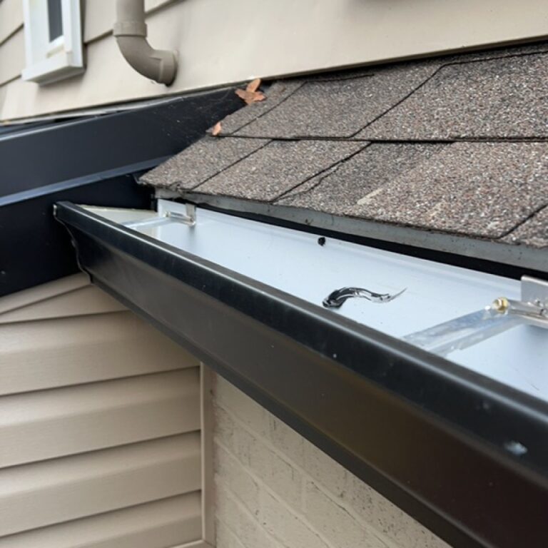 Close up view of a new gutter system installed on a shingled slanted roof by The Exterior Company.