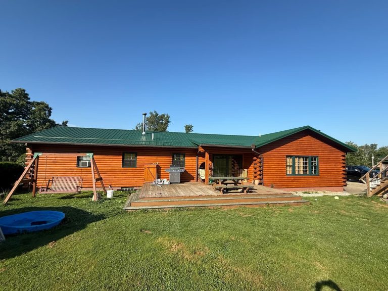 Residential log home with a green metal roof showcasing roofing and exterior construction.