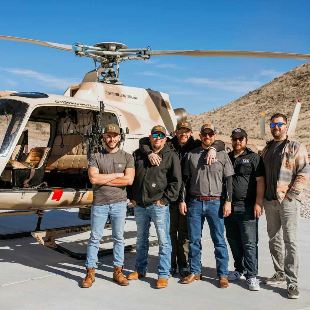 group of tec project managers standing in front of a helicopter