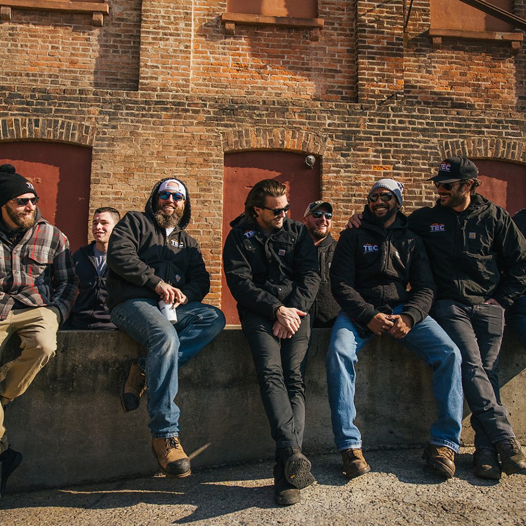 A group of TEC project managers sitting outside together on a concrete wall